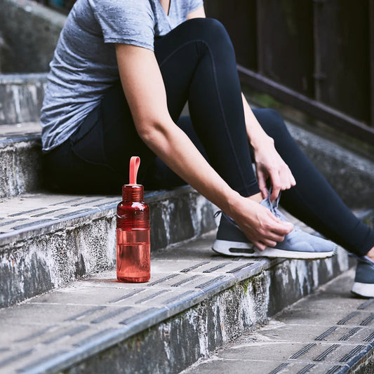 Person sitting on steps with a red water bottle next to them